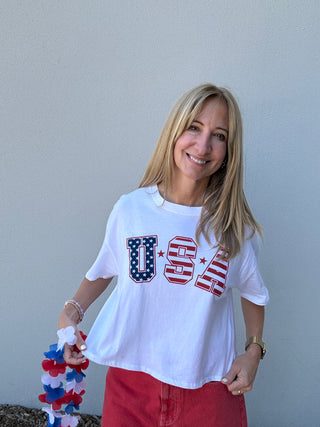 Woman wearing a white t-shirt with 'USA' print against a plain background