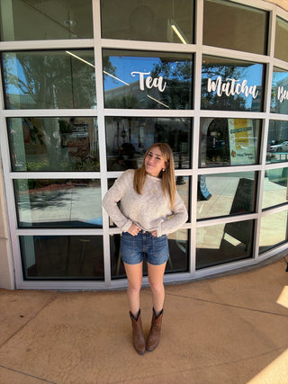 Person standing in front of a large glass window with reflections.