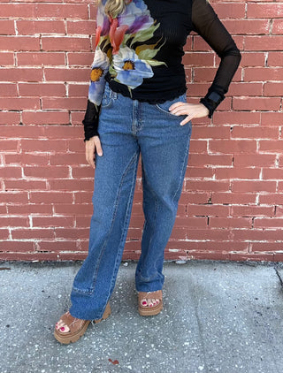 a woman wearing We The Free Risk Taker Mid-Rise Jeans - Be Bold. medium wash denim jeans