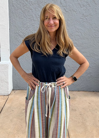 woman wearing a dark navy blue sleeveless tee shirt standing against a blue background