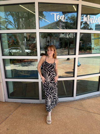 Woman standing in front of a glass door with reflections of trees and buildings.