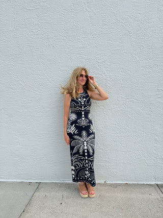 Woman wearing a black and white patterned dress against a light gray wall.