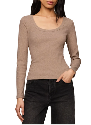 A woman modeling a fitted, long-sleeve scoop-neck knit top in a warm taupe-brown color, paired with black jeans, against a solid light beige studio background.