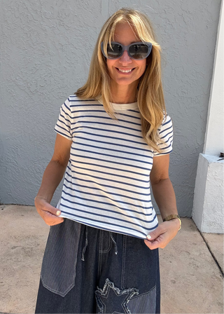 woman wearing a white tee shirt with thin blue horizontal stripes.