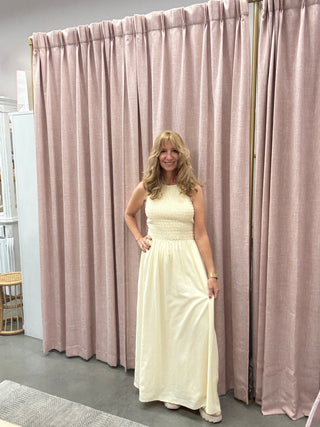 Woman in a white dress standing in front of pink curtains