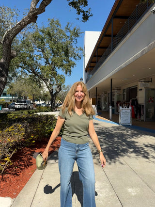 Woman standing on a sidewalk with trees and a building in the background