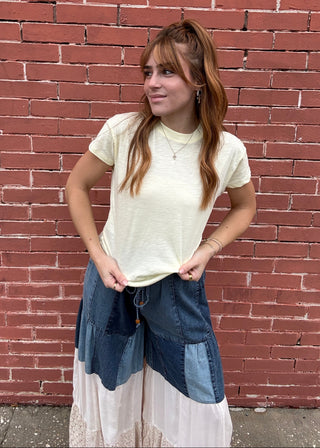 Girl wearing yellow tee shirt standing in front of a brick wall.