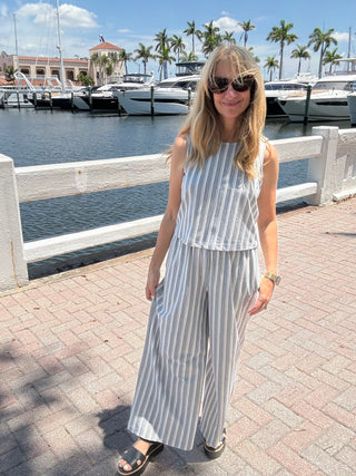 woman standing in a stripped matching outfit in front of a marina backdrop