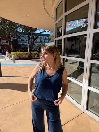 Person standing on a sidewalk with a building and trees in the background