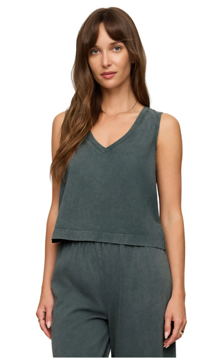 A woman modeling a dark slate gray sleeveless V-neck top and matching gray pants against a solid light beige background.