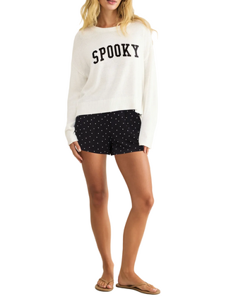 a woman wearing Z Supply  white with a Spooky graphic Sweater and black polka dots shorts