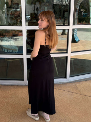 Woman in a black dress standing in front of a glass door with 'Tea Matcha' written on it.