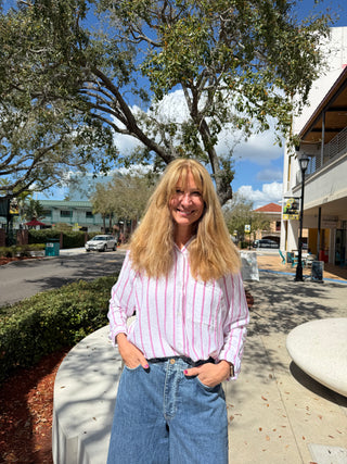 Woman standing outdoors on a sunny day with trees and buildings in the background