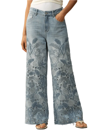 Light blue jeans with floral patterns worn by a person on a beige background