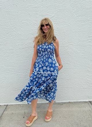 Woman wearing a blue sea life dress standing against a white wall.