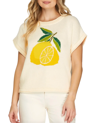 Woman wearing a light yellow t-shirt with lemon design on a plain background