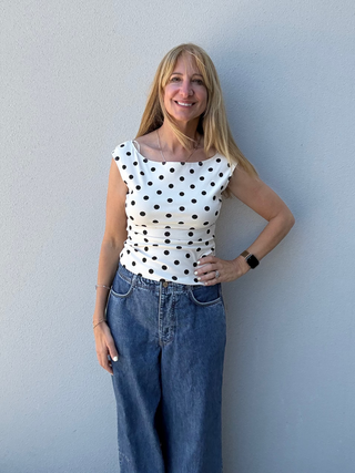 woman in front of a white wall with a polka dot top